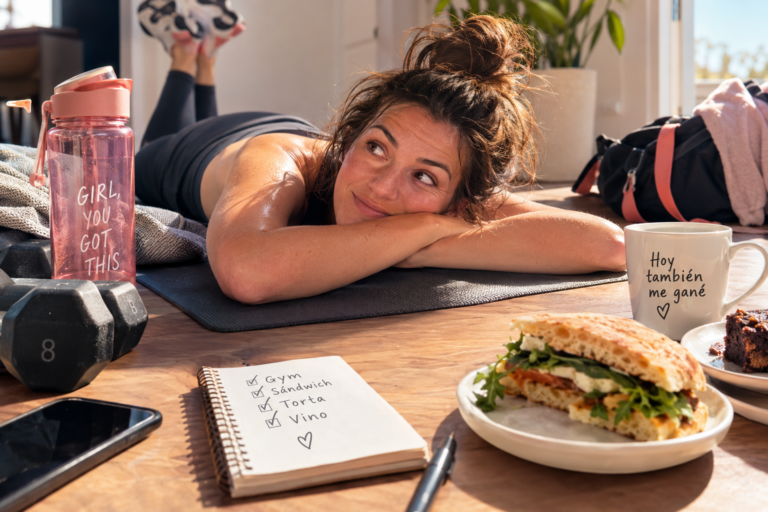Mujer sudorosa relajándose después del gimnasio con sándwich y vino.